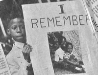 Newspaper photo of African-American youth who is holding a poster that says 'I remember.' Beneath these words is a photograph of the youth at an earlier age with his mother.