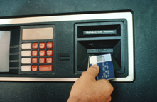Photo of person inserting a bank card into an ATM machine.