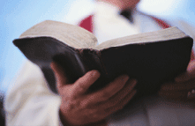 Photo of a clergy person holding a book of prayer.