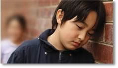 Photo of a boy with head leaning against a wall